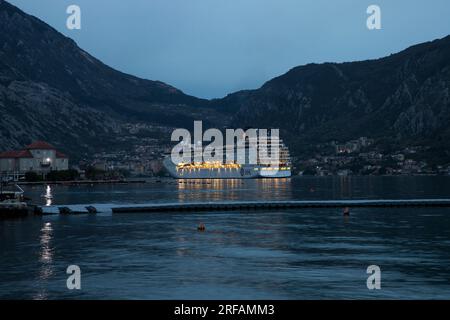 Kotor, Montenegro, 16. April 2023: Kreuzfahrtschiff MSC ARMONIA vor Anker in der Bucht von Kotor in der Abenddämmerung Stockfoto