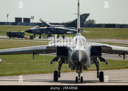 RAF Tornado GR4 Kampfflugzeuge bei RAF Waddington, Lincolnshire, Großbritannien. Ein Jet parkt, ein Flugzeug fährt zur Landebahn Stockfoto