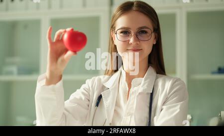 Glückliche Kardiologin, die die Herzfigur in der Hand hält Stockfoto