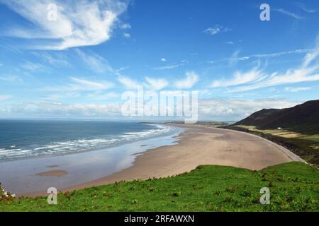 Blick von Rhossili über Rhossili Beach/Bay an einem sonnigen Augusttag auf der Halbinsel Gower mit den Rhossili Downs dahinter und dem alten Vicarage davor Stockfoto