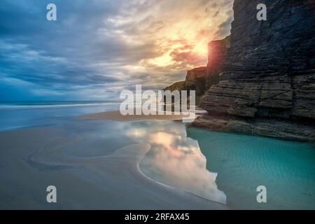 Wunderschöne Aussicht auf den Strand Las Catedrales in Lugo, Galicien, Spanien, mit den Farben des Sonnenaufgangs und dem türkisfarbenen Wasser Stockfoto