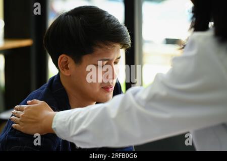 Psychologe tröstende und unterstützende männliche Patienten bei Arzttermin. Psychotherapie und psychisches Gesundheitskonzept Stockfoto