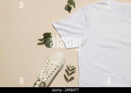 Flaches weißes T-Shirt, Sneaker mit Kopierbereich auf cremefarbenem Hintergrund Stockfoto