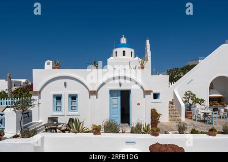 Weißes Haus mit blauer Tür und Kirche Panagia Platsani, Ia (Oia), Santorin, Griechenland Stockfoto