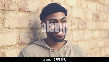 Lachender afroamerikanischer Mann mit Mütze und Piercing draußen in der Stadt Stockfoto