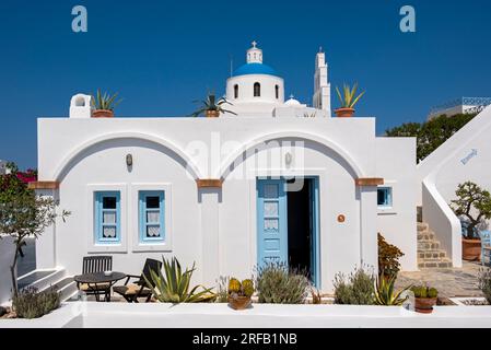 Weißes Haus mit blauer Tür und Kirche Panagia Platsani, Ia (Oia), Santorin, Griechenland Stockfoto