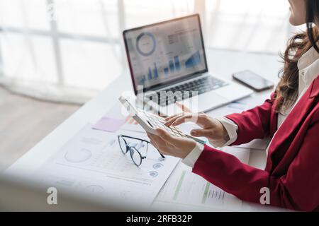 Nahaufnahme der Hände einer Geschäftsfrau mit einem Taschenrechner, um die Finanzen und Einnahmen des Unternehmens sowie das Budget zu prüfen. Geschäftsfrau, die die monatlichen Ausgaben berechnet Stockfoto