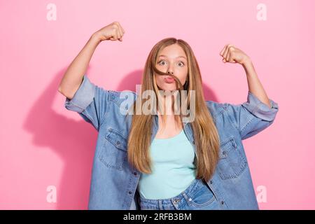 Foto eines attraktiven jungen Teenagers Fäuste beugen Muskeln Schnurrbart elegant Jeanskleidung isoliert auf pinkfarbenem Hintergrund Stockfoto