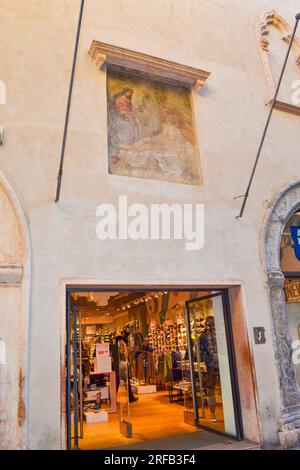Eingang zum Modegeschäft im alten Gebäude mit biblischen Gemälden an der Wand über der Via Giuseppe Mazzini - bemerkenswerte Straße mit vielen Designern Stockfoto