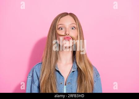 Foto eines reizenden jungen Mädchens mit gefälschtem Schnurrbart Strähne in elegantem Denimkleid isoliert auf pinkfarbenem Hintergrund Stockfoto