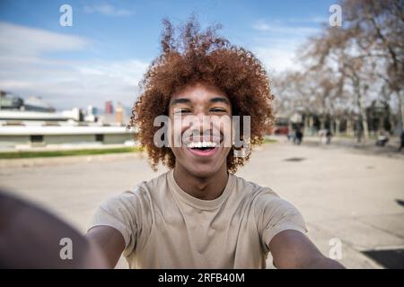 Ein glücklicher, gutaussehender Mann, der entspannt lächelt und auf der Straße in die Kamera schaut und ein Selfie macht. Ein entspannter, glücklicher Mann, der lacht und starrt und die Kamera hält Stockfoto