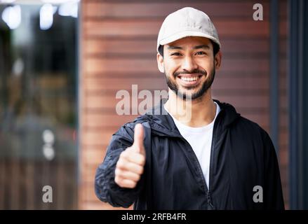 Porträt, asiatischer Mann und Kurier mit Daumen nach oben im Freien für Zustellung, Erfolg und vielen Dank mit einem Lächeln. Happy, Face und ein japanischer Lieferant mit Stockfoto