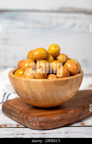 Große grüne Oliven in einer Holzschüssel. Oliven auf weißem Holzhintergrund. Mediterrane Küche. Veganes Essen Stockfoto