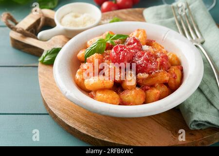 Kartoffelgnocchi. Traditionelle hausgemachte Kartoffelgnocchi mit Tomatensoße, Basilikum und Parmesan auf türkisfarbenem rustikalem Küchentisch. Traditi Stockfoto