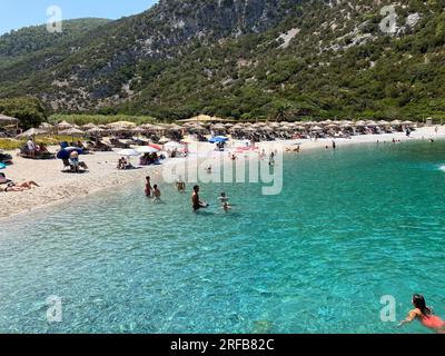 Skopelos, Griechenland. 02. Aug. 2023. Die Leute verbringen den heißen Sommertag an einem Strand auf der Sporades Insel Skopelos. Einige sitzen unter ihren eigenen bunten Schirmen, andere unter Strohschirmen, die gemietet werden können. Das ist auch nach griechischem Recht richtig, das besagt, dass die Bürger freien, ungehinderten Zugang zu den auf jeden Fall öffentlichen Stränden haben müssen. Das griechische Gesetz erkennt keine privaten Strände an. Kredit: Alexia Angelopoulou/dpa/Alamy Live News Stockfoto