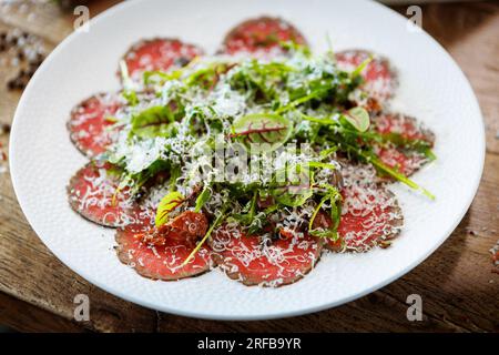 Rindercarpaccio. Borettanzwiebeln, sonnengetrocknete Tomaten, Trüffeldressing, Rucola-Salat, Parmesan-Käse. Italienische traditionelle Antipasti-Snacks für l Stockfoto