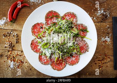 Rindercarpaccio. Borettanzwiebeln, sonnengetrocknete Tomaten, Trüffeldressing, Rucola-Salat, Parmesan-Käse. Italienische traditionelle Antipasti-Snacks für l Stockfoto