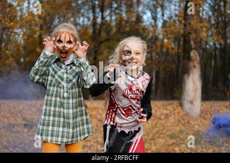 Kinder Mädchen, die Halloween-Kostüme tragen und sich draußen schminken, haben Spaß. Horizontales Foto Stockfoto