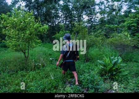 22. Juni 2023, Churachandpur, Manipur, Indien: Ein bewaffneter Kuki-Jugendlicher wandelt im Dschungel, während er in das Dorf Dampi in Churachandpur im nordöstlichen indischen Staat Manipur zum Frontdienst aufbricht. Die Jugend der Kuki-Zo-Stämme in Manipur hat sich bewaffnet, um ihr Dorf vor externen Bedrohungen zu schützen, insbesondere vor ihren Feinden, den Meiteis, die im Tal leben. Mit einem starken Gefühl der Einheit und der Entschlossenheit, ihr Land zu schützen, haben die Dorfjugend eine Verteidigungskraft gebildet und sich mit von der Manipur-Regierung genehmigten Gewehren bewaffnet. Zusammenstöße zwischen den Geisteswissenschaften Stockfoto