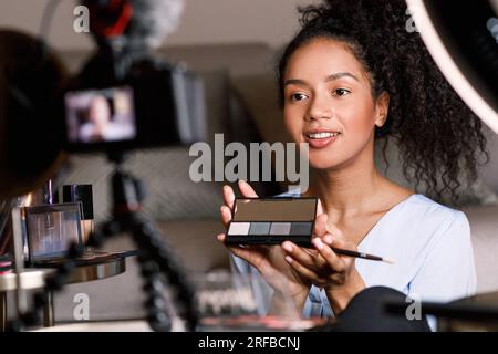 Junger Influencer, der Make-up-Tutorial macht, während er vor einer Kamera sitzt Stockfoto
