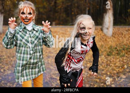 Kinder Mädchen, die Halloween-Kostüme tragen und sich draußen schminken, haben Spaß. Horizontales Foto Stockfoto