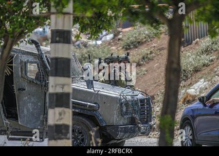 Jordantal, Palästina. 02. Aug. 2023. Israelische Soldaten stehen während der Belagerung des Gebiets in der Nähe des Schussangriffs auf ein Auto jüdischer Siedler in der Nähe der Siedlung Hamra im nördlichen Westjordanland neben ihren militärischen Patrouillen Wache. Ein zu schnell fahrendes Auto eröffnete das Feuer auf ein Auto, das Siedlern in der Nähe der Al-Hamra-Siedlung gehörte, und verwundete sie. Die israelische Armee umzingelt das Gebiet weiterhin, um den Täter zu verhaften. (Foto von Nasser Ishtayeh/SOPA Images/Sipa USA) Guthaben: SIPA USA/Alamy Live News Stockfoto