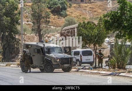 Jordantal, Palästina. 02. Aug. 2023. Israelische Soldaten stehen während der Belagerung des Gebiets in der Nähe des Schussangriffs auf ein Auto jüdischer Siedler in der Nähe der Siedlung Hamra im nördlichen Westjordanland neben ihren militärischen Patrouillen Wache. Ein zu schnell fahrendes Auto eröffnete das Feuer auf ein Auto, das Siedlern in der Nähe der Al-Hamra-Siedlung gehörte, und verwundete sie. Die israelische Armee umzingelt das Gebiet weiterhin, um den Täter zu verhaften. (Foto von Nasser Ishtayeh/SOPA Images/Sipa USA) Guthaben: SIPA USA/Alamy Live News Stockfoto