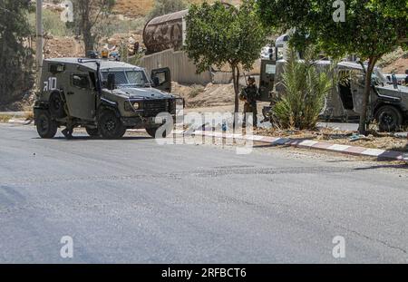 Jordantal, Palästina. 02. Aug. 2023. Israelische Soldaten stehen während der Belagerung des Gebiets in der Nähe des Schussangriffs auf ein Auto jüdischer Siedler in der Nähe der Siedlung Hamra im nördlichen Westjordanland neben ihren militärischen Patrouillen Wache. Ein zu schnell fahrendes Auto eröffnete das Feuer auf ein Auto, das Siedlern in der Nähe der Al-Hamra-Siedlung gehörte, und verwundete sie. Die israelische Armee umzingelt das Gebiet weiterhin, um den Täter zu verhaften. (Foto von Nasser Ishtayeh/SOPA Images/Sipa USA) Guthaben: SIPA USA/Alamy Live News Stockfoto