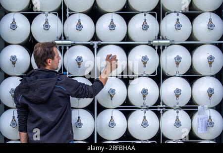 Rostock, Deutschland. 02. Aug. 2023. Ein Mitarbeiter überprüft im neuen Depot der Rostocker Straßenbahn AG (RSAG) biomethanhaltige Druckbehälter. Biomethan ist ein zertifiziertes Gas aus landwirtschaftlichen Abfällen. Mit diesem Kraftstoff haben die Biomethan-Busse eine CO2-Bilanz, die der von Elektrobussen mit grünem Strom vergleichbar ist. Nach sechs Monaten Umbauarbeiten wird der Standort für Linienbusse für alternative Antriebssysteme umgebaut. Kredit: Jens Büttner/dpa/Alamy Live News Stockfoto