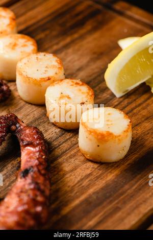 Gemischte gegrillte Meeresfrüchte auf Holzbrett, dunkler Hintergrund. Blick von oben. Stockfoto
