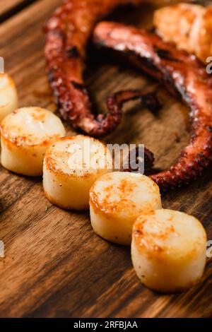 Gemischte gegrillte Meeresfrüchte auf Holzbrett, dunkler Hintergrund. Blick von oben. Stockfoto