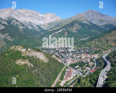 LUFTAUFNAHME. Die Stadt Bardonecchia im Susa-Tal mit Rocca Bernauda (3225m) in der Ferne und Bramafam-Fort auf der linken Seite. Piedmont, Italien. Stockfoto