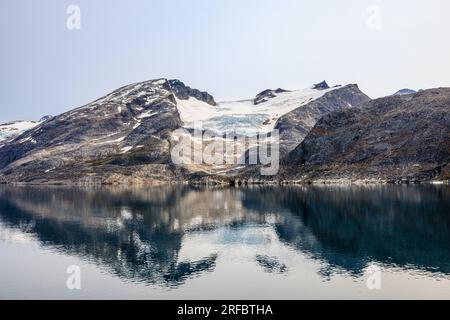 Wunderschöne arktische Landschaft mit felsigen Bergen und Gletschern mit Schnee im stillen Wasser des Prinzen christian Sound grönland Stockfoto