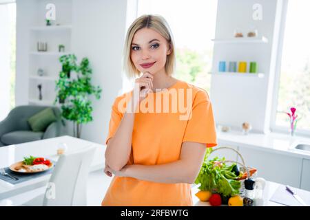 Portrait von hübschem Mädchen Arm berühren Kinn betrachten, denken Sie darüber nach, bereiten Sie das Abendessen zu geräumige, moderne Hausküche drinnen vor Stockfoto