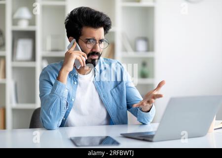 Besorgter Indischer Männlicher Unternehmer, Der Probleme Mit Einem Laptop Am Arbeitsplatz Hat Stockfoto