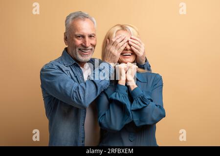 Ein hübscher, liebevoller Senior-Mann, der seine Frau zum Geburtstag überrascht Stockfoto
