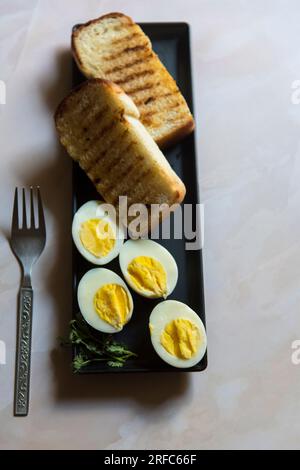 Frühstücksessen Zutaten Brot und Ei auf einem schwarzen Tablett. Stockfoto