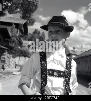 1960er Jahre, historisch, tagsüber und ein junger deutscher Junge in der traditionellen bayerischen Lederhose, Deutschland, mit Alpenhut. Aus dem süddeutschen Raum Bayern stammend, waren Lederhosen oder Lederhosen Outfits für die Bewohner der Berg- und Landstriche des Landes. Stockfoto