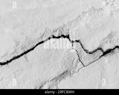Großer langer gewundenen Riss an alter Putzwand. Speicherplatz kopieren. Schwarzweißfoto. Selektiver Fokus. Stockfoto