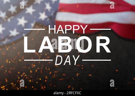 Happy Labor Day Konzept. Amerikanische Flagge mit verschiedenen Bauwerkzeugen auf dunklem Steinhintergrund, mit Platz für Text. Stockfoto