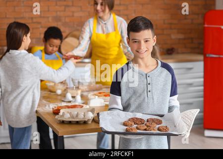 Kleiner Junge mit während des Kochkurses in der Küche zubereiteten Plätzchen Stockfoto