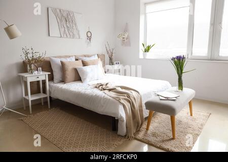 Helles Schlafzimmer mit wunderschönen Irisblumen auf der Nachtbank Stockfoto