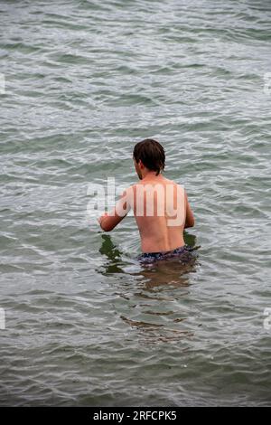 Mann schwimmt in kaltem Wasser. Kaltwasserbaden. Wilder Schwimmer. Wildes Schwimmen. Stockfoto