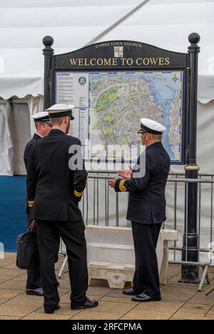 königliche Marineoffiziere in der cowes Week Segelregatta auf der Insel wight. Marineoffiziere, die vor einem "Willkommen bei cowes" -Schild während der cowes Week sprechen. Stockfoto