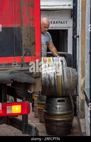 Ein Drayman, der Fässer Bier an ein öffentliches Haus liefert. ale wird von einem Drayman an einen Eingang geliefert. Schwere Fässer Bier per Hand zu einem Pub zu bringen. Stockfoto
