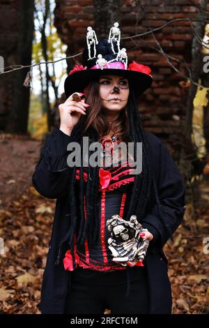 Eine Frau im Bild von Baron Saturday. Das Modell trägt ein Korsett, eine Strickjacke und einen Hut mit Skelettfiguren und Posen mit einem CI Stockfoto