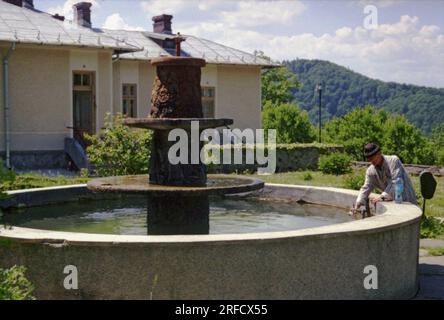 Bezirk Neamt, Rumänien, 1999. Ein Mann, der Plastikflaschen mit Wasser aus einem öffentlichen Zierbrunnen füllt. Stockfoto