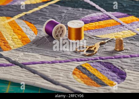 Nähzubehör auf einer Mini-Steppdecke mit geometrischem Muster in Orange-Lila Stockfoto