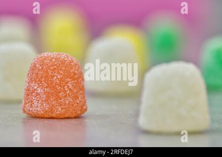 Gummi Tropft zuckerbeschichtete Süßigkeiten, Makro mit seitlichem Blickwinkel auf einem Tisch mit selektivem Fokus. Beliebte traditionelle Süßigkeiten auf Gelatinebasis, die weltweit hergestellt werden. Stockfoto