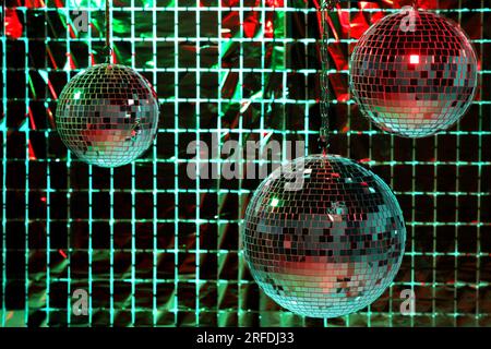Glänzende Disco-Bälle gegen einen Partyvorhang unter farbigen Lichtern Stockfoto